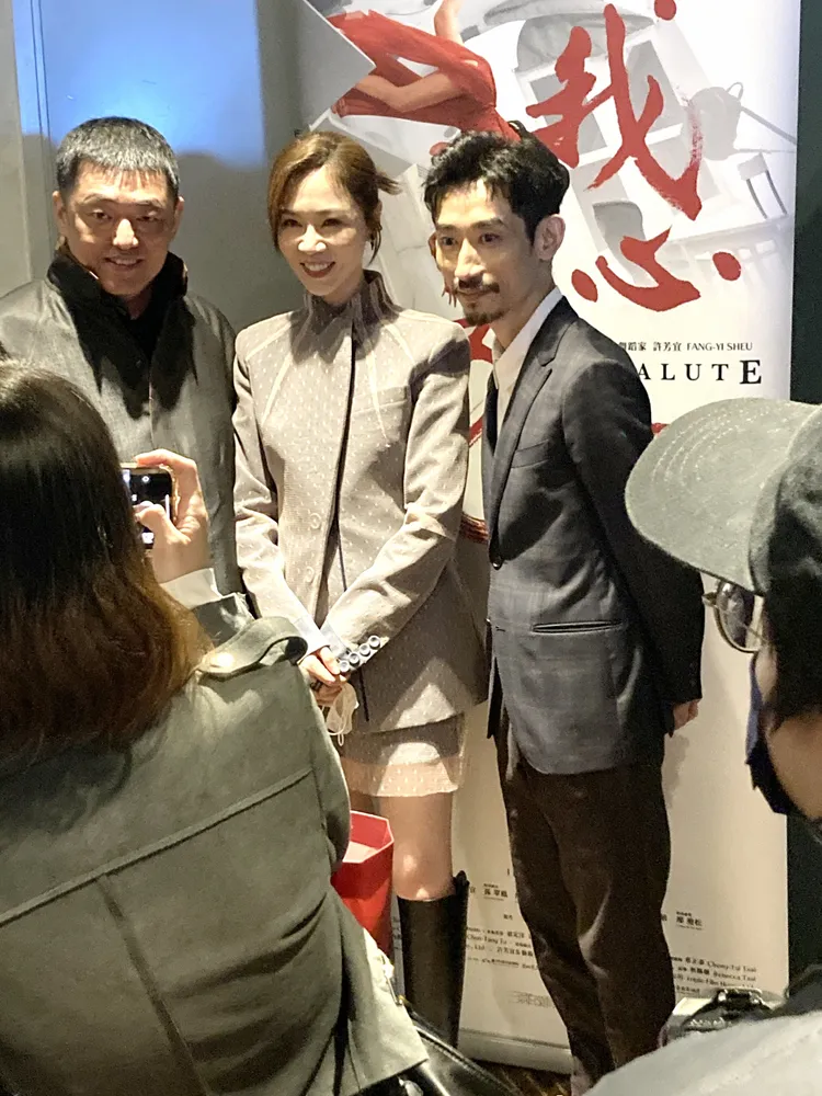 「劇場女神」謝盈萱（中）與演員陳竹昇（右），在電影宣傳背板前合照。特勤中心攝