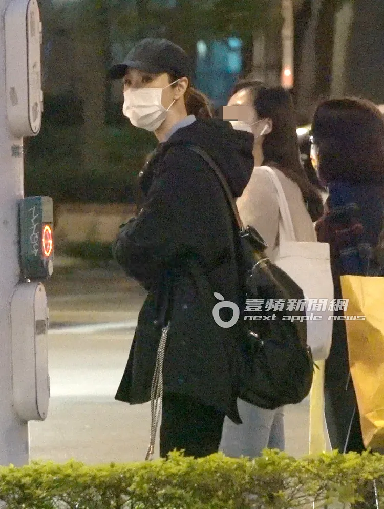 影后謝盈萱戴口罩、穿著一身黑，走到松高路口等紅綠燈，不時探頭察看左右來車。特勤中心攝