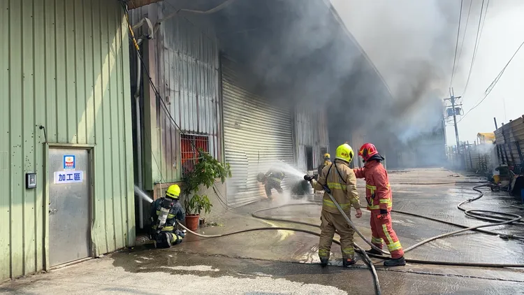 消防人員切割鐵捲門射水搶救。讀者提供