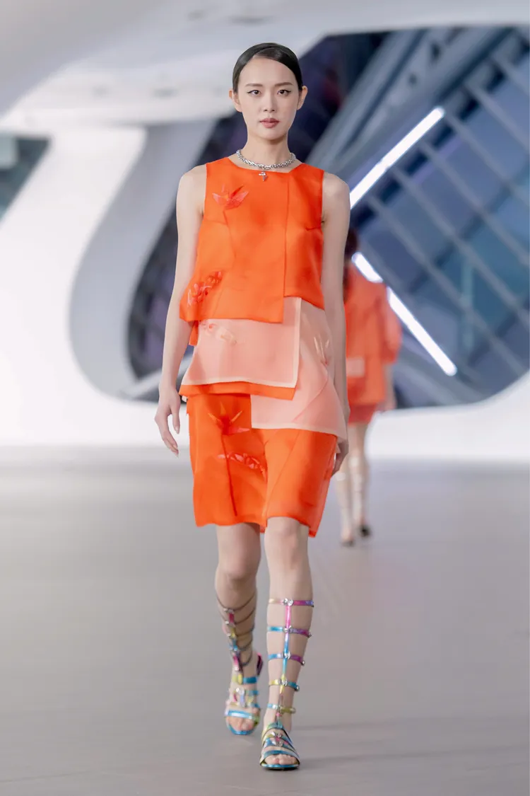 7片裁片連衣裙，圖騰以具東方意象的天堂鳥與蘭花剪影形貌，以蘇繡中「網繡」的綁紗技法呈現，極致的手繡針法於烏干紗上勾勒出幾何圖形的鏤空美學。品牌提供