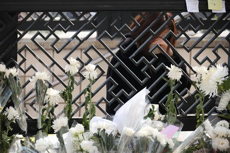 首爾梨泰院踩踏事件現場擺滿致哀花束，一名年輕女孩蹲在地上掩面流淚。路透社