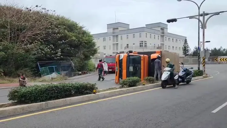 宅配貨車翻覆，自行脫困駕駛一臉茫然呆坐人行道上。許逸民攝