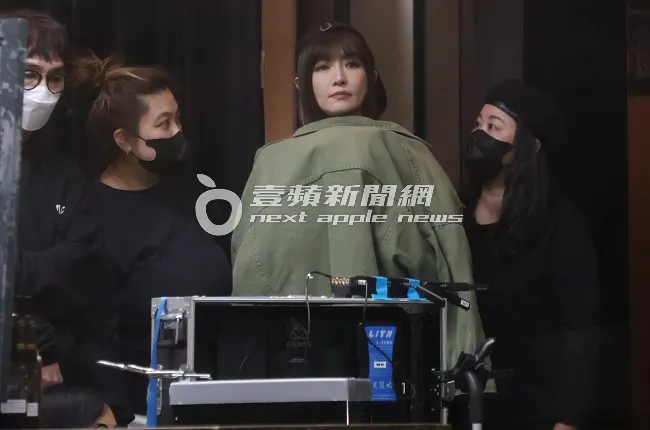 女神謝金燕（中）披著外套保暖，看錄影回放片段，助理在旁查看妝容。特勤中心攝