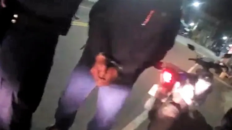 警方強勢上銬、將何男帶回警局。讀者提供