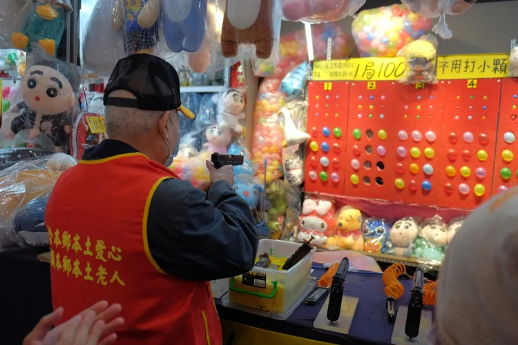 獨居老人逛夜市，不忘回味射氣球。逢甲夜市提供