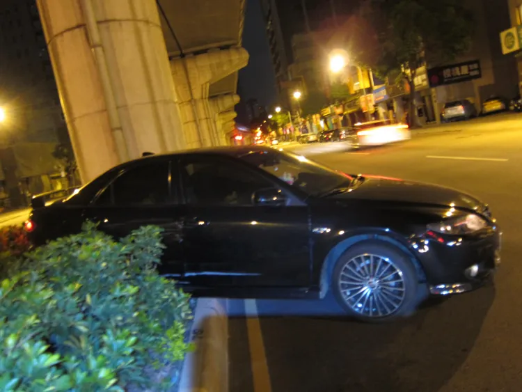 自小客車撞倒機車後開上安全島、車體擦損。讀者提供