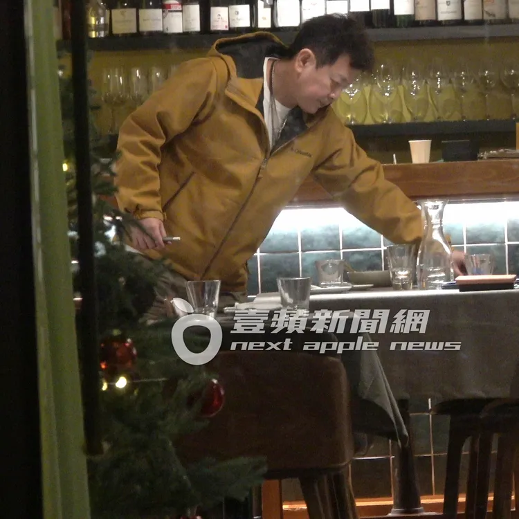 庹宗康收拾桌面物品，一手拿著加熱電子菸繼續抽。特勤中心攝