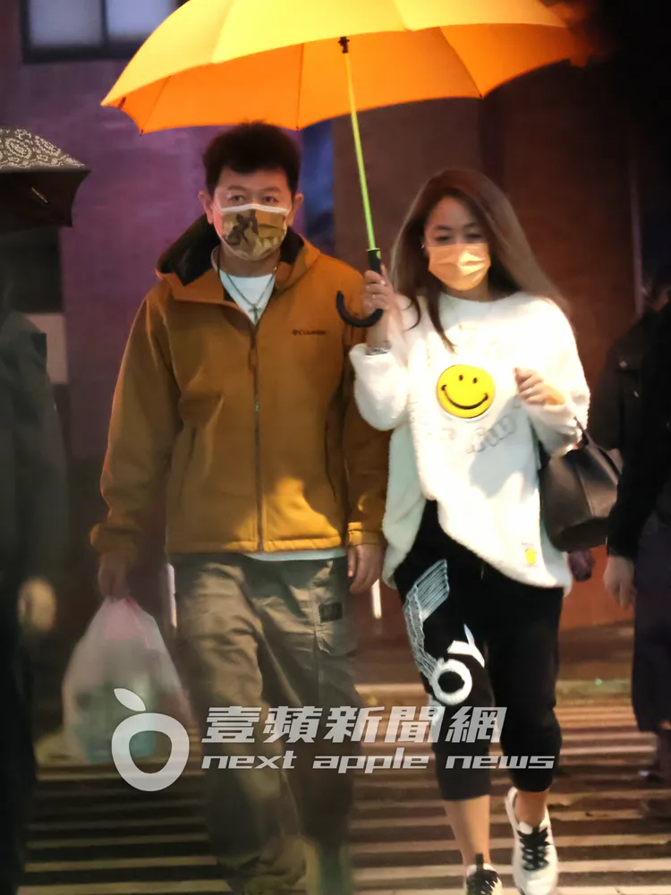 庹宗康（左）當起挑夫拿著好幾袋食物，與「關島妹」嫩妻Kiki，一起撐傘過馬路。特勤中心攝