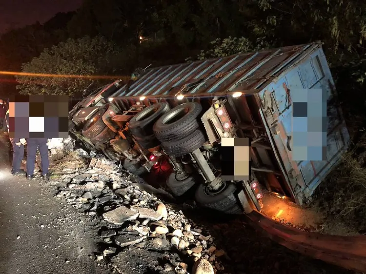 聯結車將整排護欄連根拔起，側翻在邊坡。讀者提供