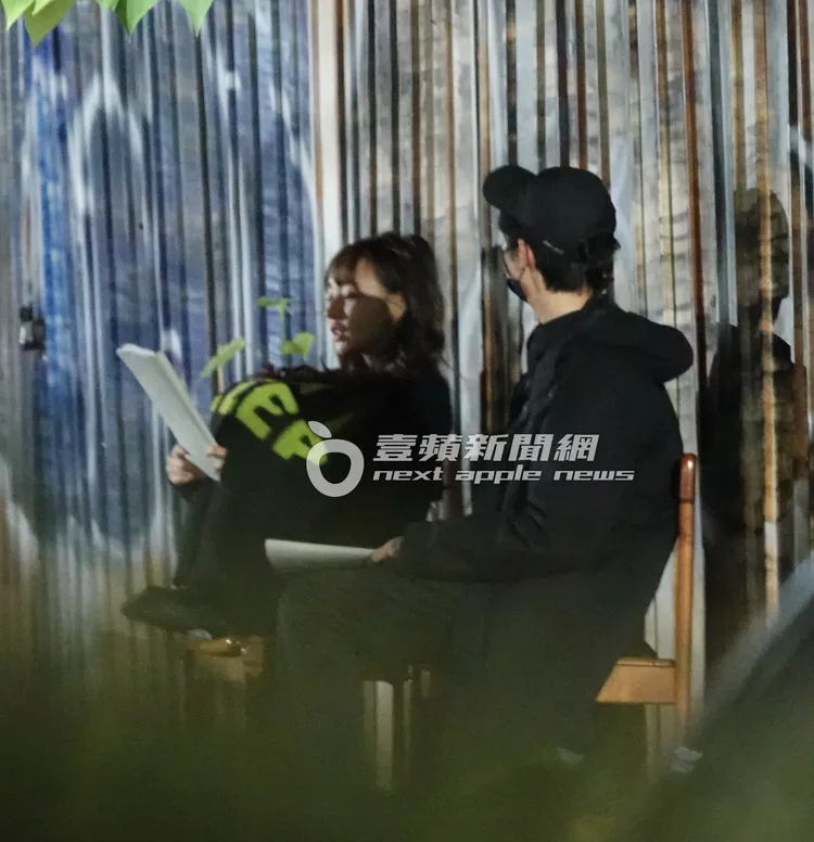 林襄（左）手拿劇本，在椅子上抱腿取暖，和男學員溫馨對戲。特勤中心攝