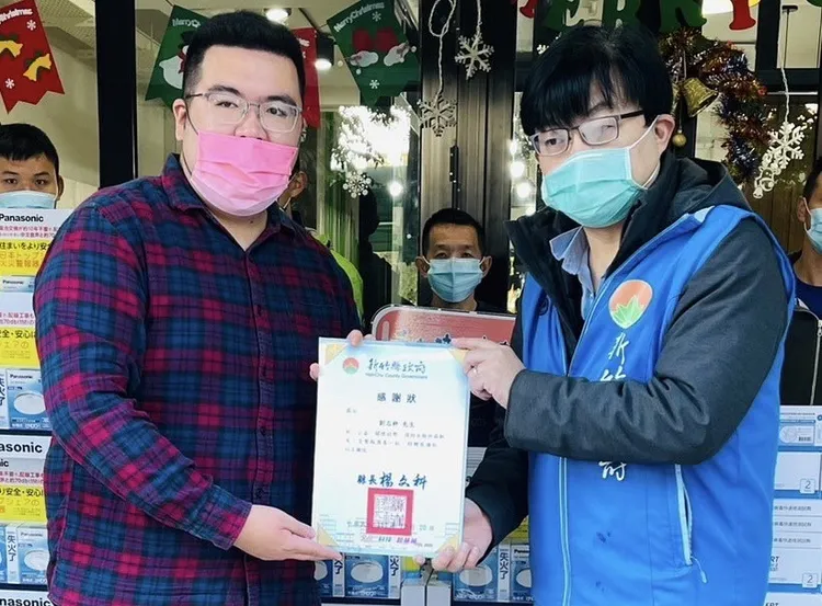 愛的萌芽福利理事長劉志枰（左），今天（19日）捐贈100顆日製光電式偵煙式住宅用火災警報器以及1600千劑快篩給予新竹縣政府。協會提供