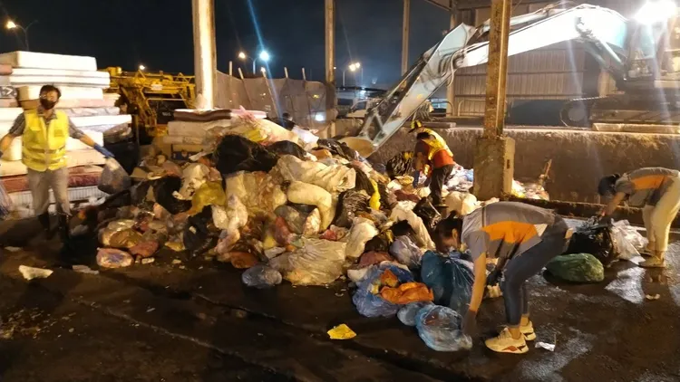 台中市梧棲清潔隊將垃圾車召回並傾倒當日收取的成堆垃圾，清潔隊員漏夜翻找30分鐘終於尋獲裝現金的藍色現金袋。台中市環保局提供