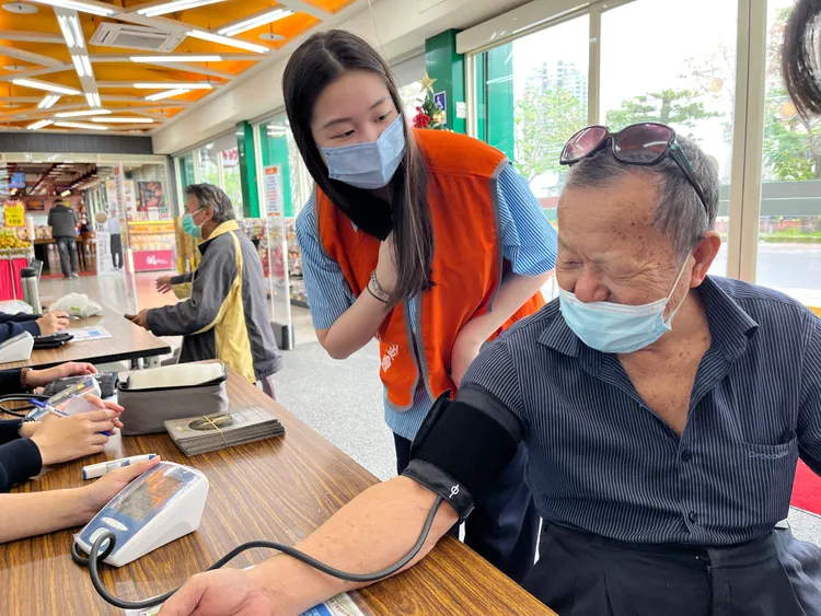 採買年貨前聖母護專學生關懷長輩並協助量測血壓健檢。弘道理人福利基金會提供