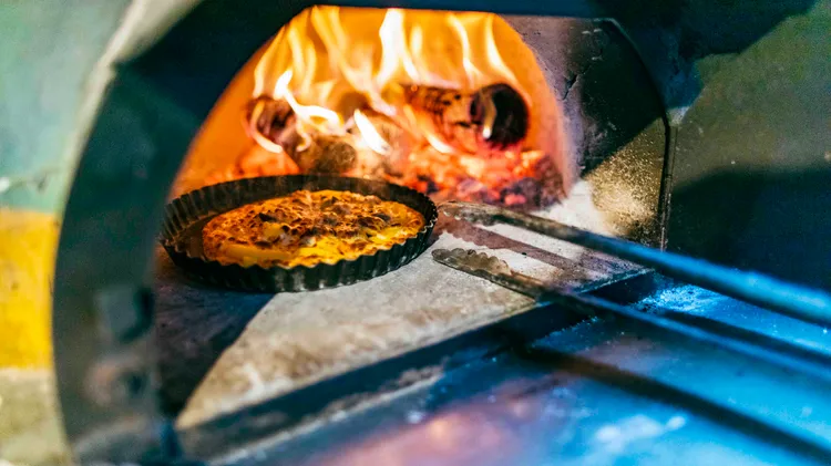 協助旅人將手作PIZZA放入餐車窯烤爐。古和純攝