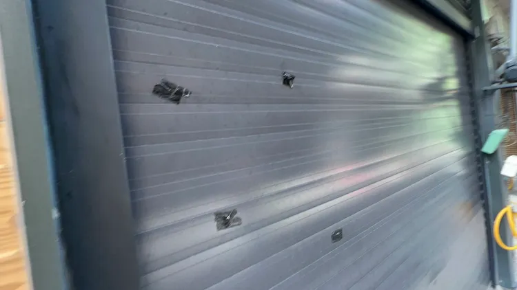 一樓鐵捲門都是彈孔，已被貼上黑色膠布。侯昌騰攝