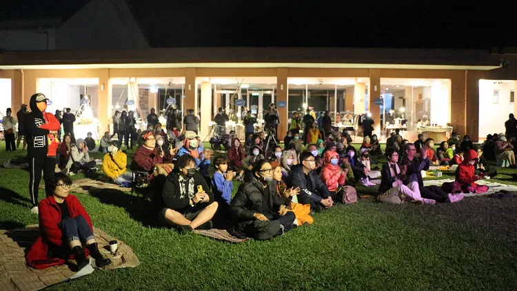 台東縣長饒慶鈴（左１）與觀眾席地而坐聆聽原民歌聲。台東縣政府提供