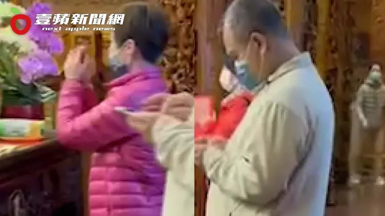林益世滑手機，和虔誠拜拜的老婆形成強烈對比。讀者提供