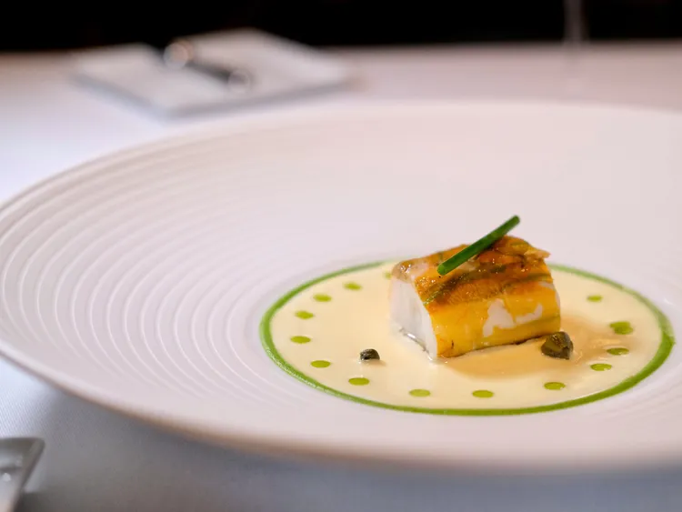 「蒸櫛瓜花鱈魚卷/櫛瓜醬/奶油魚湯/酸豆醬/蝦夷蔥/魚皮」，以櫛瓜花為主體，卻不見其形體，原來是蒸煮後包覆了細嫩的莫瑞鱈魚。葉盛耀攝