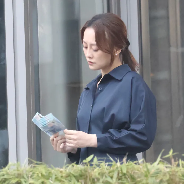 女星璟宣將清潔公司服裝脫掉，手拿一疊大鈔在數錢。特勤中心攝