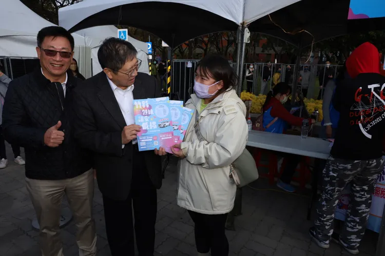 新竹縣長楊文科與竹縣不動產開發商業同業公會榮譽理事長吳國寶發送摸彩券給現場兌換的民眾。新竹縣府提供