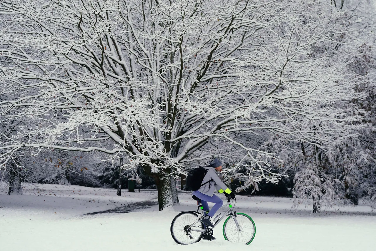 民眾騎車行經積雪覆蓋的公園。美聯社