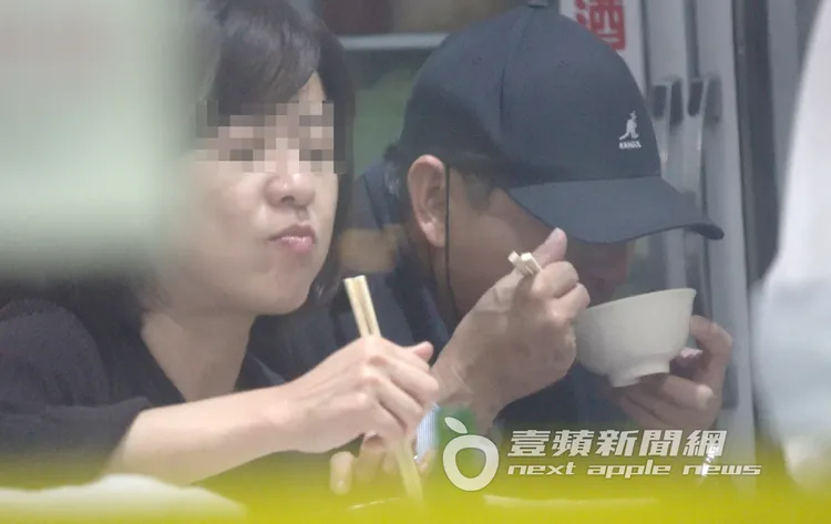 謝震武（右）低頭嗑飯，OL女則在一旁幫忙整理餐具及擺盤。特勤中心攝