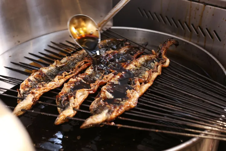 使用長鐵籤串，視生鰻燒烤焦化狀態進行補串翻面及澆水降溫。翁王信攝