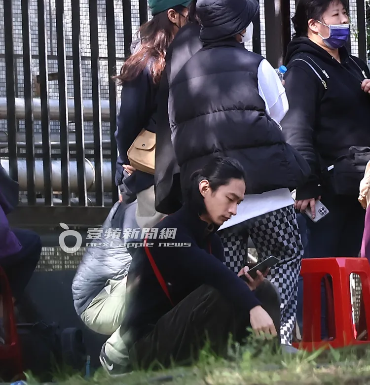 黃河坐在路旁滑手機等待拍攝。特勤中心攝