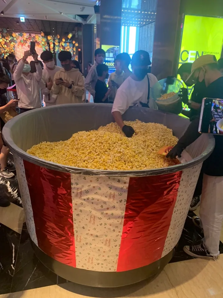 男子分裝桶內部分爆米花給影城內排隊者。吳慧芬攝