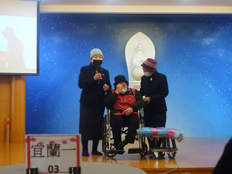 罹患小兒麻痺的謝女士（中），平時坐在特製圓板凳行動，今天（25日）前往慈濟宜蘭聯絡處上台分享自己的人生故事，談到已逝的父母一度哽咽。慈濟提供