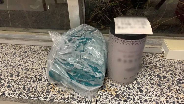 疑似裝爆裂物的容器與另一個塑膠袋被放在輔大一間大樓門口。新莊警分局提供