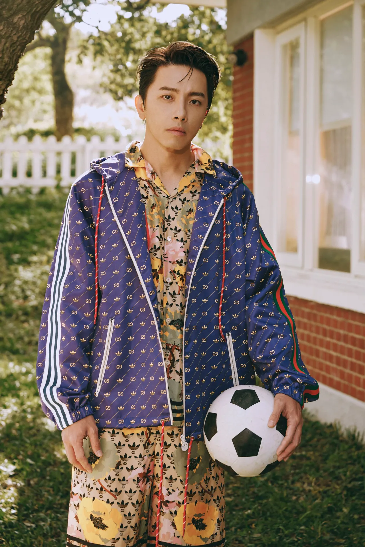 坤達穿上佈滿雙品牌Logo印花的保齡球衫套裝,搭配搶眼的藍紫色運動外套,一側袖子飾有adidas白色三條紋,另一側則飾以Gucci經典的綠紅綠織帶。品牌提供