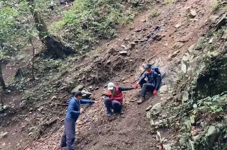 搜救人員架設繩索，並上前攙扶他。消防局提供