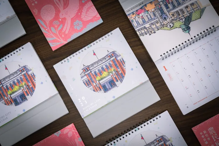 新竹市政府以「繪旅行」手法紀錄城市景點，推出2023年月曆、桌曆及喜氣的兔年農民曆，14日起限量兌換。市府提供