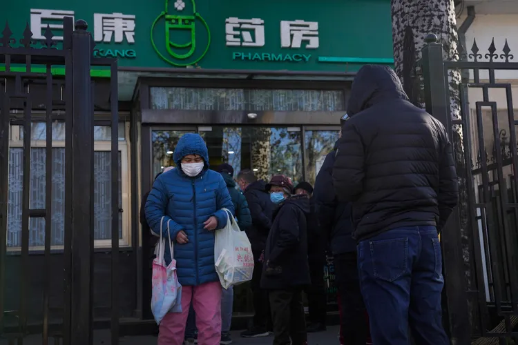 北京市民11日踏出一家藥房，買了兩大袋藥品與防疫物資。美聯社