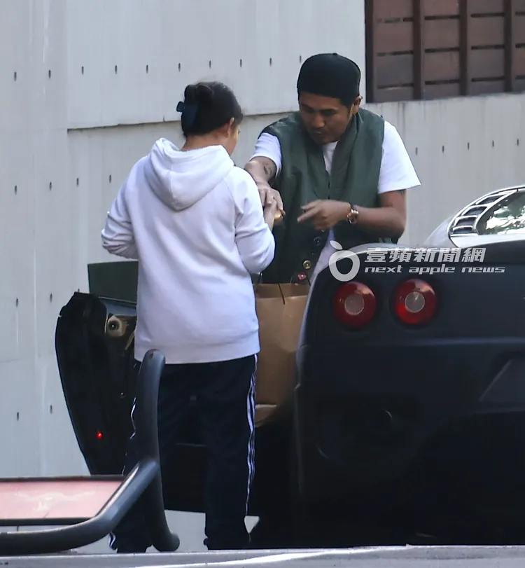 狗狗開心地在車邊，曹格（右）把紙袋交給幫傭。特勤中心攝