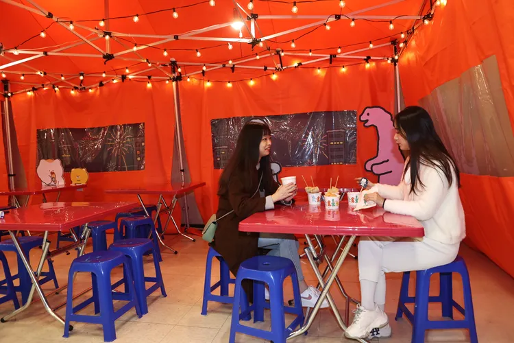小吃區以橘紅色布幕、昏黃小燈串還原韓國街邊布帳馬車場景。翁玉信攝