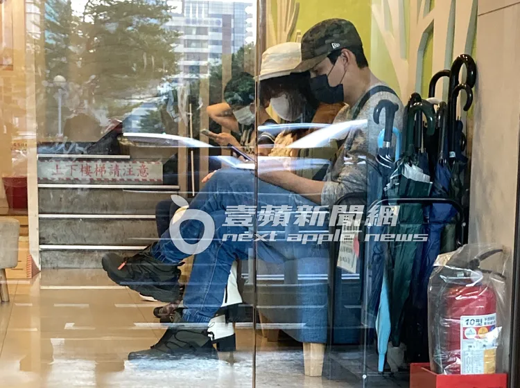 孫協志（右）和女友夏宇童坐在診所沙發上休息，邊滑手機候診。特勤中心攝