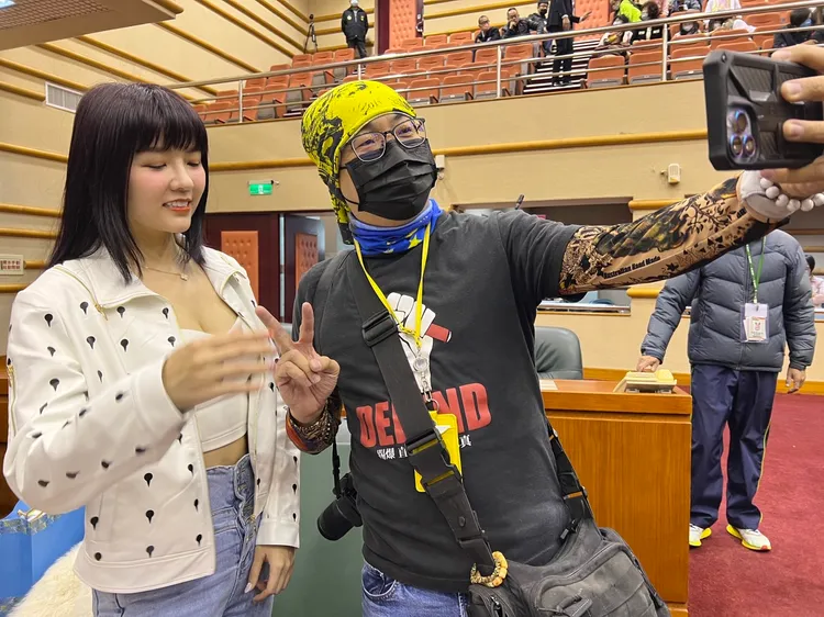 記者與顏議員合影卻因手勢過高而當場被糾正。讀者提供