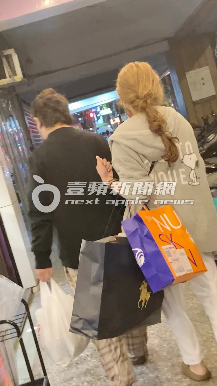 納豆（左）與情牽5年女友依依，一身居家休閒服打扮，提著大包小包及食物，走進木柵的華廈。特勤中心攝