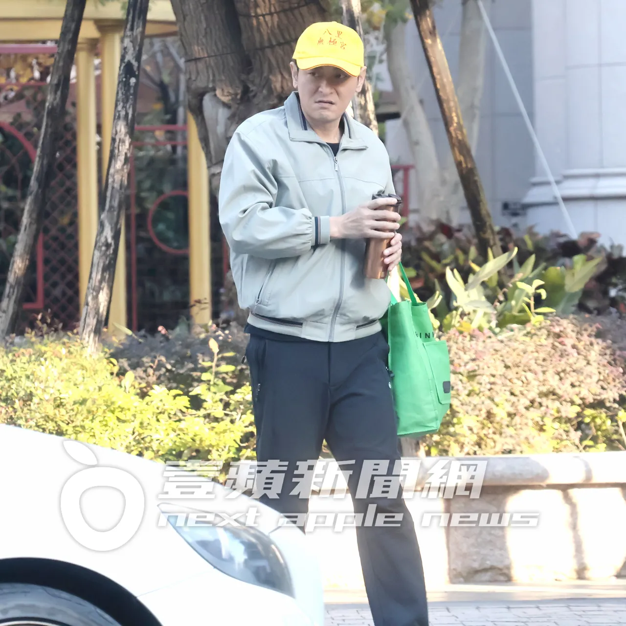 陳冠霖穿著夾克外套、頭戴宮廟帽,手上還提著購物袋跟保溫瓶。特勤中心攝