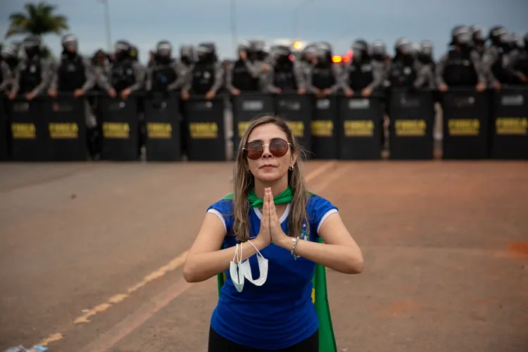 巴西前總統博爾索納羅支持者的「文組」在警方前擺好和平的姿勢。路透社