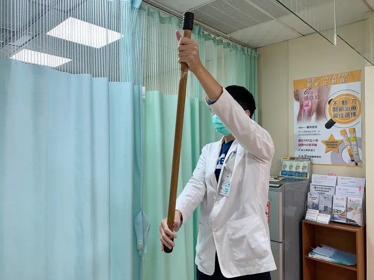 第二式「棍棒運動」，站著，受傷側手抓上端，另側較有力的手抓下端並出力帶動棍棒往前或往側邊。讀者提供