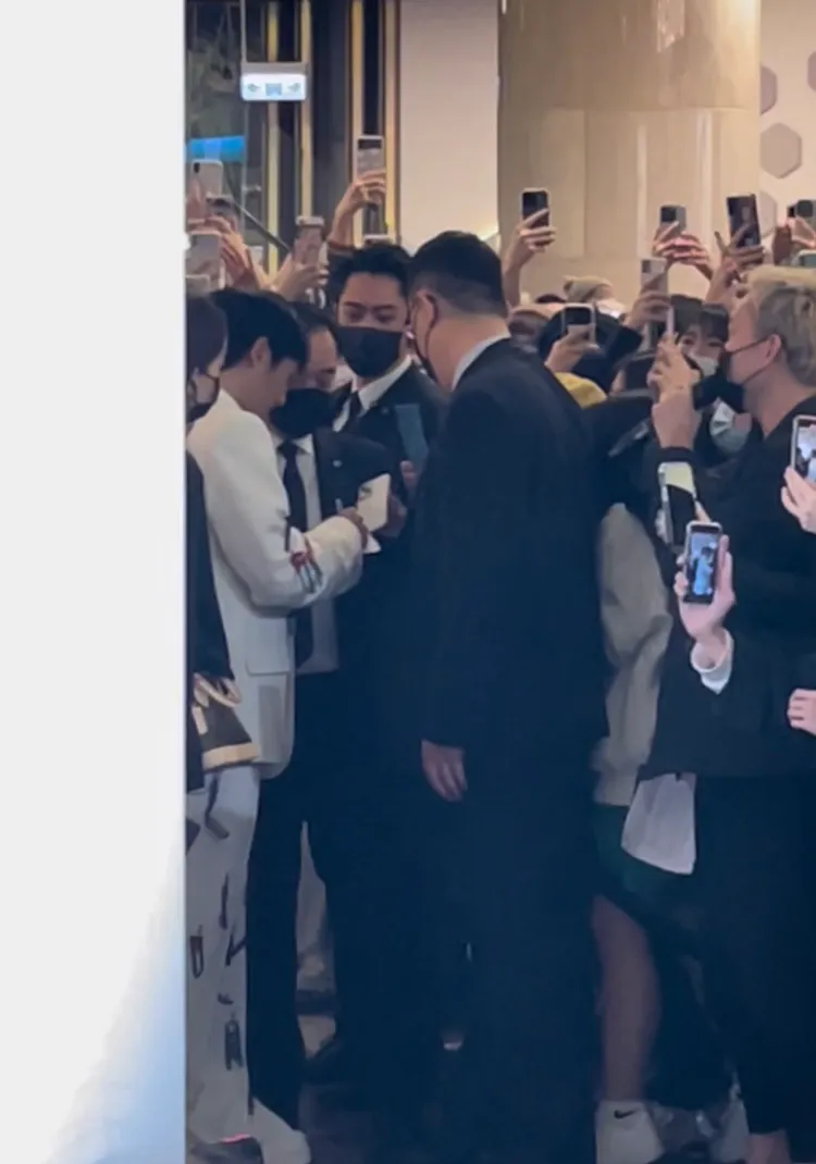 丁海寅（白衣者）在站上背板前，沿路替一旁粉絲簽名，親和力滿分。讀者提供