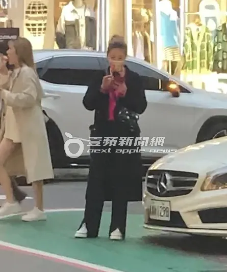 身穿桃紅色上衣的小禎，喜氣洋洋站在路邊滑手機。特勤中心攝