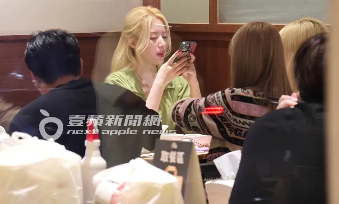 舒華（中）吃飽飯後，邊滑手機邊吐出舌頭舔嘴唇。特勤中心攝