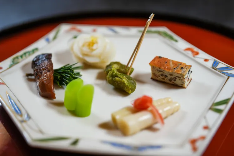 展現季節風味的八寸，從中央的炸茶葉，接著烤牛蒡豆腐、嫩筍、菜心、蕈菇到百合鱗莖，一路順時針由苦韻吃到甘甜。田欣雲攝