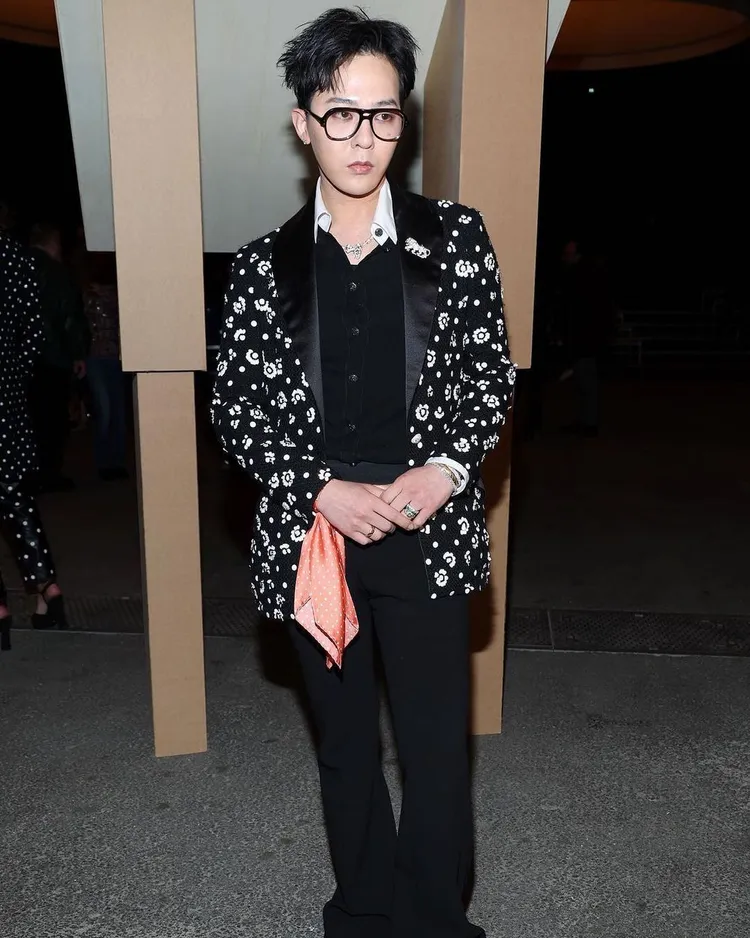 GD穿上香奈兒花瓣圖案西裝外套搭配白領黑襯衫、黑西褲，並戴上黑框眼鏡、手繫亮橘絲巾、獅子胸針、珍珠項鍊和Coco Crush戒指，風格率性。翻攝jiyo_ng1808 IG