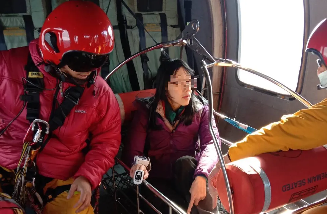 女登山客因腳傷受困山區,空勤出動黑鷹直昇機緊急救援,順利將傷者吊掛上機艙,檢視傷勢。空勤總隊提供