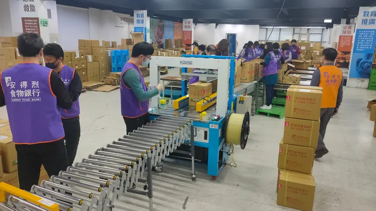 志工在食物銀行倉庫內包裝食物箱。黃子騰攝